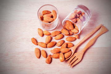 Almonds in brown bowl on wooden background