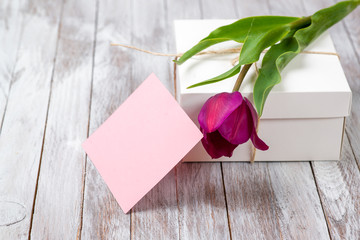 Fresh purple tulips bouquet and gift box on wooden background. Space for text.