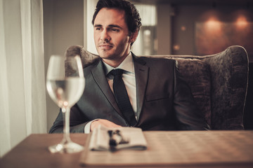 Confident young man sitting in restaurant waiting for somebody