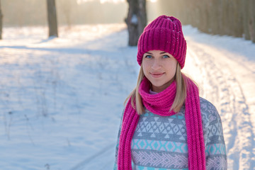 Portrait of young girl in pink hat and scarf in the winter fores