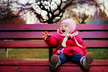 Positive little girl sitting on a bench