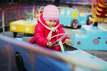 The little girl sits in the blue car