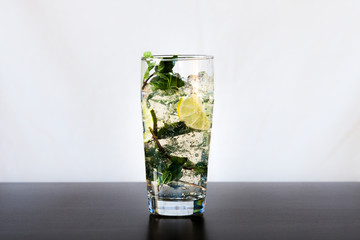 Mojito cocktail with lime, fresh mint and ice in high glass on a black table.
