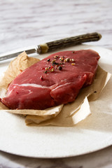Raw beef tenderloin with peppercorns.