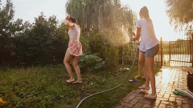 Slow motion footage of happy family playing in backyard with garden hose