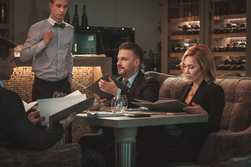 Group of successful business people with menu in restaurant