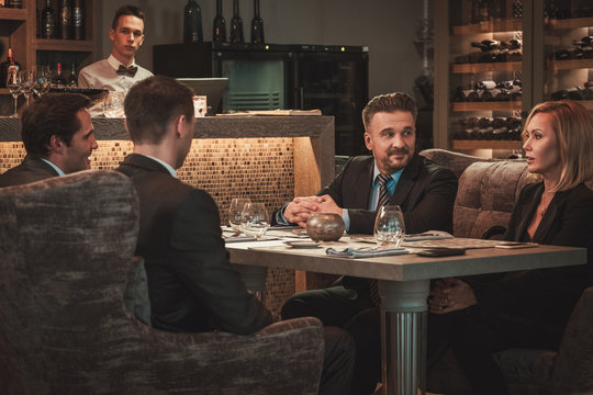 Group of successful business people discussing during business dinner in restaurant