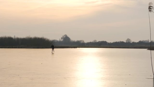 Ice skating in the countryside during sunset in the Netherlands