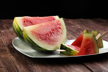 Watermelon slice popsicles and ripe striped watermelon on a rust
