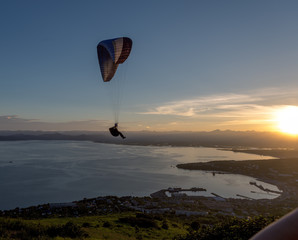 Paraglider flying over vespers Petropavlovsk-Kamchatsky on the background of the Avachinsky bay at sunset - Kamchatka, Russia