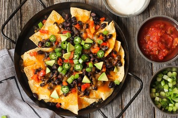 Classic Nachos with Tortilla chips melted cheese sauce jalapeno peppers avocado salsa and sour...