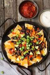 Classic Nachos with Tortilla chips melted cheese sauce jalapeno peppers avocado salsa and sour cream / Game day food