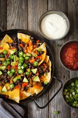 Classic Nachos with Tortilla chips melted cheese sauce jalapeno peppers avocado salsa and sour cream / Game day food
