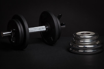 Fototapeta na wymiar Dumbbell and barbell discs for workout on black background