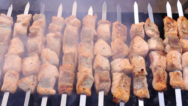 cut pieces of sturgeon fish strung on a skewer roasting on the grill, barbecue outdoors. HD