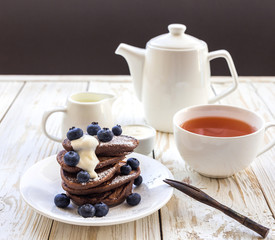 Hot tea and buckwheat chocolate pancakes with blueberries