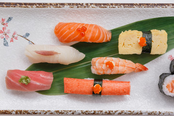 Sushi Set Include Maguro, Hamachi, Salmon, Kani, Shrimp, Tamagoyaki and Salmon Maki Roll Served with Wasabi and Prickled Ginger on Japanese Painted Stone Plate.