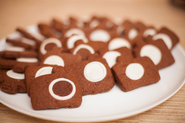 Fototapeta na wymiar Chocolate cookies in photocamera shape on plate, shallow dof