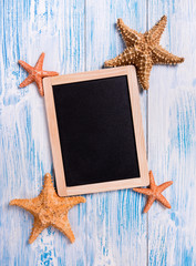 Tropical frame with starfishes on rustic wooden background