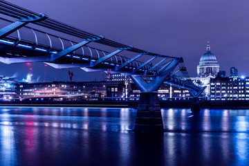 London skyline on River Thames at night with Millennium Bridge and St Paul's Cathedral reflections
