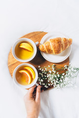 Woman hands holding cup of tea. Top view of breakfast in bed