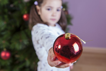 Fototapeta na wymiar Little girl shows ornaments for Xmas Tree
