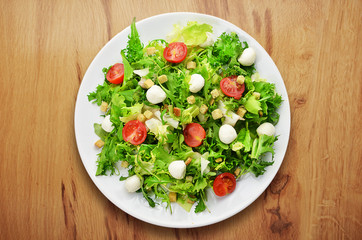 Salad on white plate on wooden table