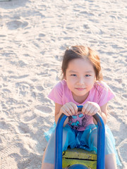 happy Asian child on a seesaw in sunset light,sand background