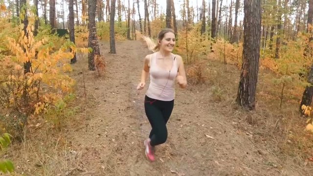 Slow motion of happy smiling woman jogging at autumn park