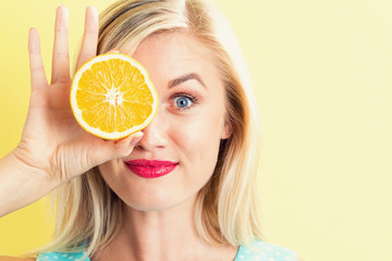 Happy young woman holding oranges halves