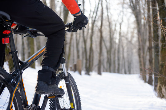 Mountain Biker Riding Bike on the Snowy Trail in Beautiful Winter Forest. Free Space for Text.