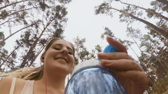 4K video from camera attached to bottle of young smiling woman running at park