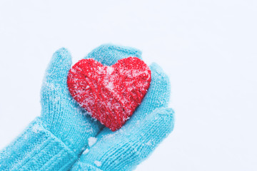 Blue knitted gloves with woolen heart. St. Valentine's Day greeting