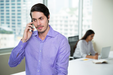 Serious young businessman talking on mobile phone
