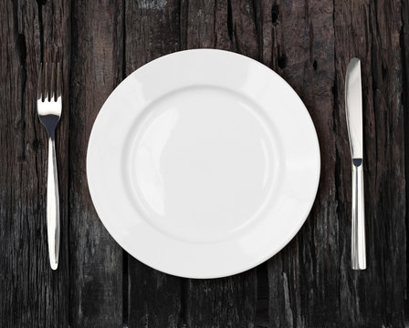 white empty dinner plate setting on old dark wooden table