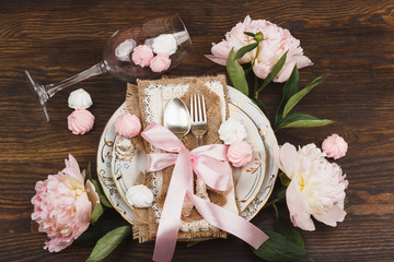 Light pink peonies and tableware on the wooden table