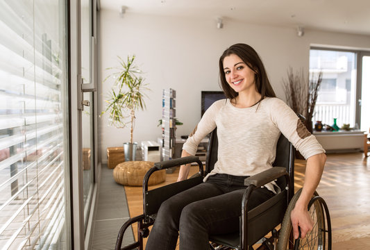 Young Disabled Woman In Wheelchair At Home In Living Room.