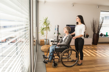 Disabled senior woman in wheelchair with her young daugher.