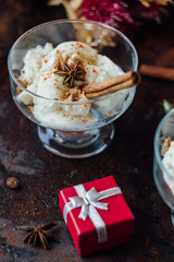 White ice cream with cinnamon and star anise on black rustic board.