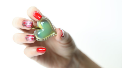 Красивая рука с красным маникюром и сердцем в руках