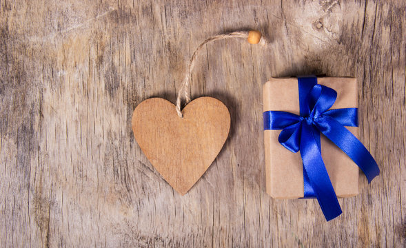 Gift box with blue bow and Valentine. Surprise on Valentine's Day. Wooden heart. Copy space. Valentine's day. 