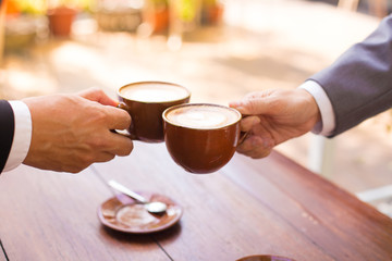 Business talk and hands shake at a coffee shop with two cups of latte