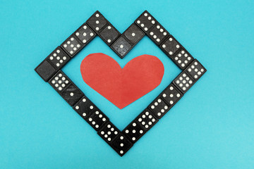 Homemade heart of dominoes on a blue background.