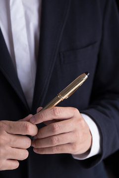 A man in black casual suit holding a gold fountain pen for sign the contract in formal way
