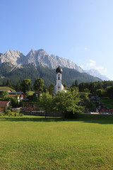 A beautiful church and cemetery in the village Grinau with Zugspitze in the background