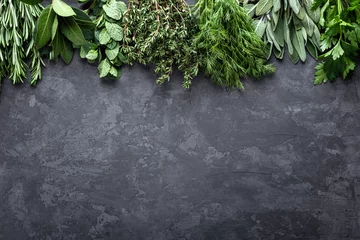 Wall murals Aromatic fresh herbs on dark stone background with space for text