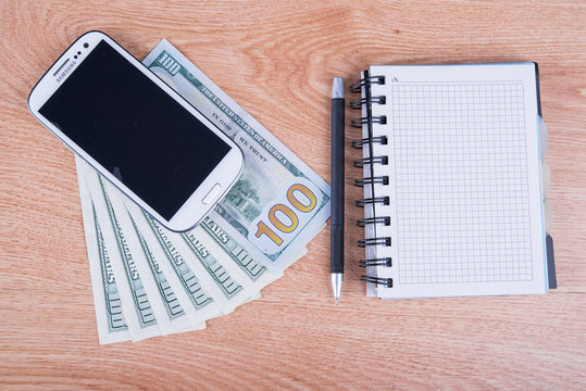 smartphone and a notebook with dollars