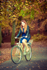 Fototapeta na wymiar Redhead lady cycling in park.