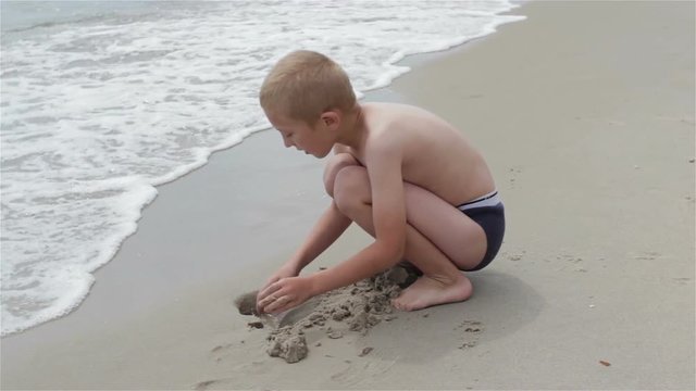 Boy digging a pit sea/Boy hands digging in the sand a pit on the shoreline of the sea