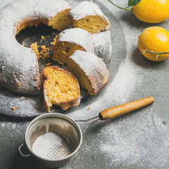 Homemade gluten-free lemon bundt cake with sugar powder over grey concrete background, selective focus, square crop